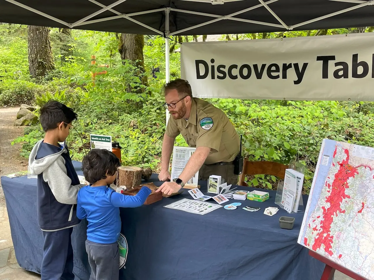 Park ranger leading a hands-on “Discovery Table” activity for children featuring nature exhibits and educational materials