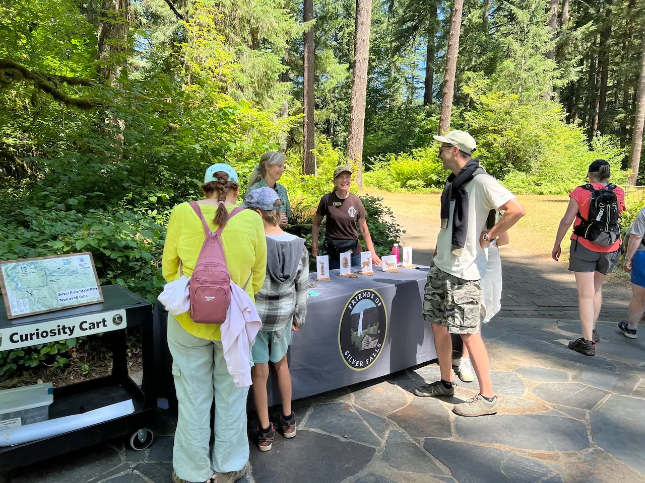 A “Curiosity Cart” and outreach table hosted by Friends of Silver Falls, where park visitors and families are learning about local wildlife and nature exhibits