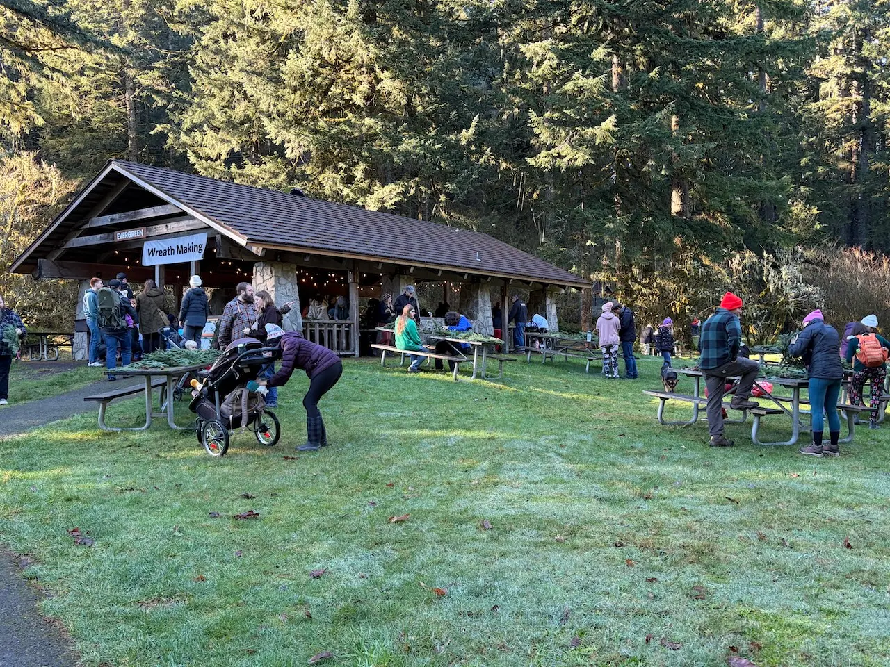 Families and visitors gathering for a festive winter wreath-making event at a rustic forest shelter